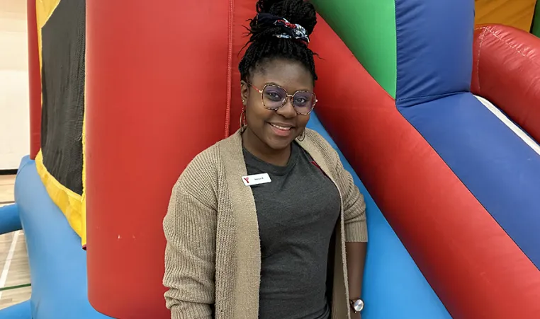 [Image] Akosua at a Y Winnipeg children's event standing in front of a bouncy castle