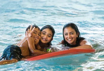 Three Kids Playing with a Flutter Board in the Pool