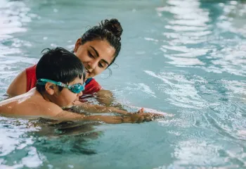 Swimming instructor teaching a young swimmer in the pool