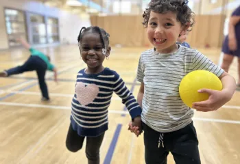 two young school age kids smiling at camera in gymnasium