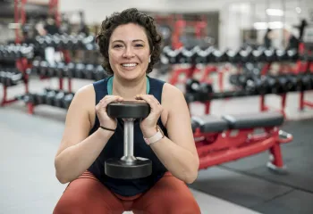 smiling female squatting while holding a dumbell