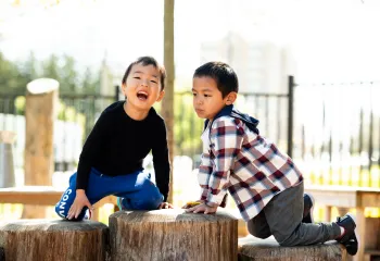 2 young boys playing outside in a playground