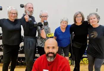 Y instructor, Javi, posing with Judy and class