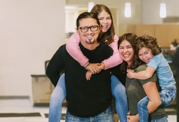 family of 4 smiling at camera