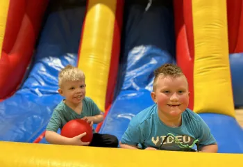 2 boys playing at bottom of a bouncy castle