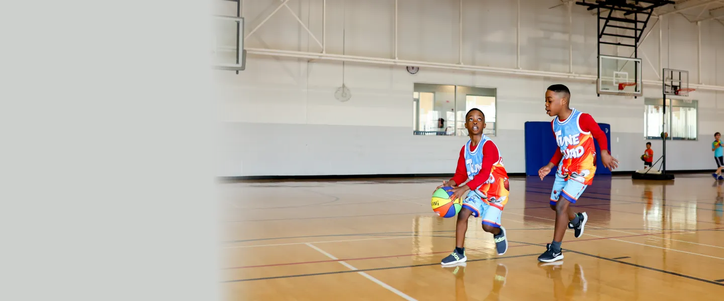 2 young boys playing basketball in the gymnasium