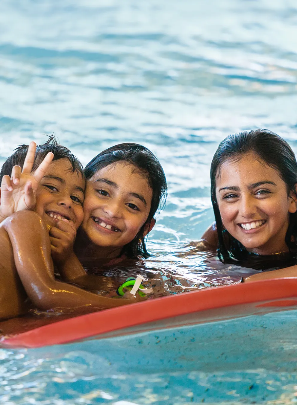 Three Kids Playing with a Flutter Board in the Pool