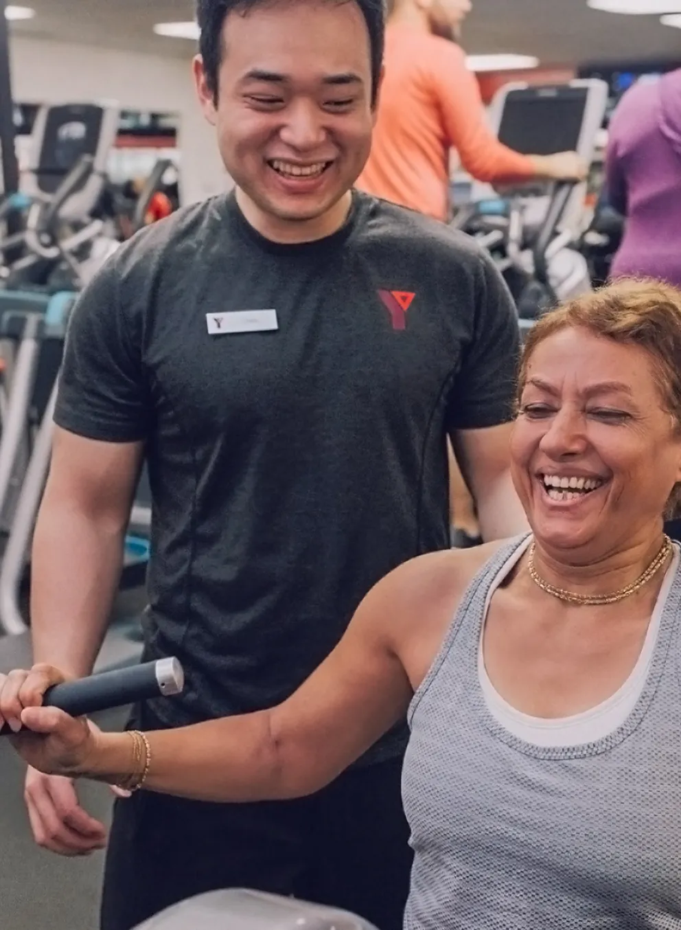 Fitness Staff With Woman Using Resistance Equipment