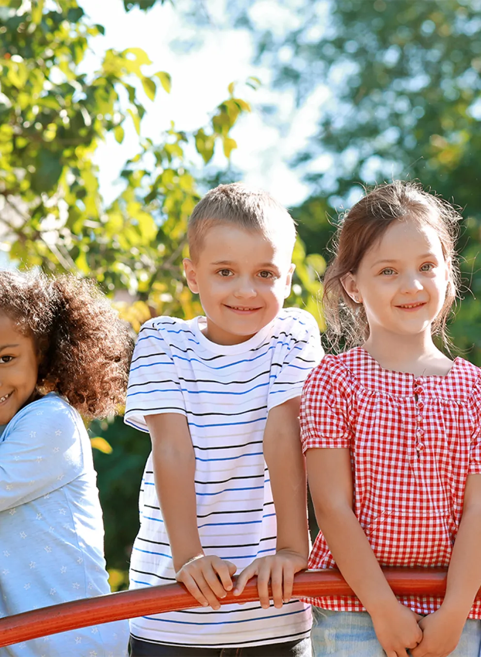 group of children smiling at camera playing in the sunshine