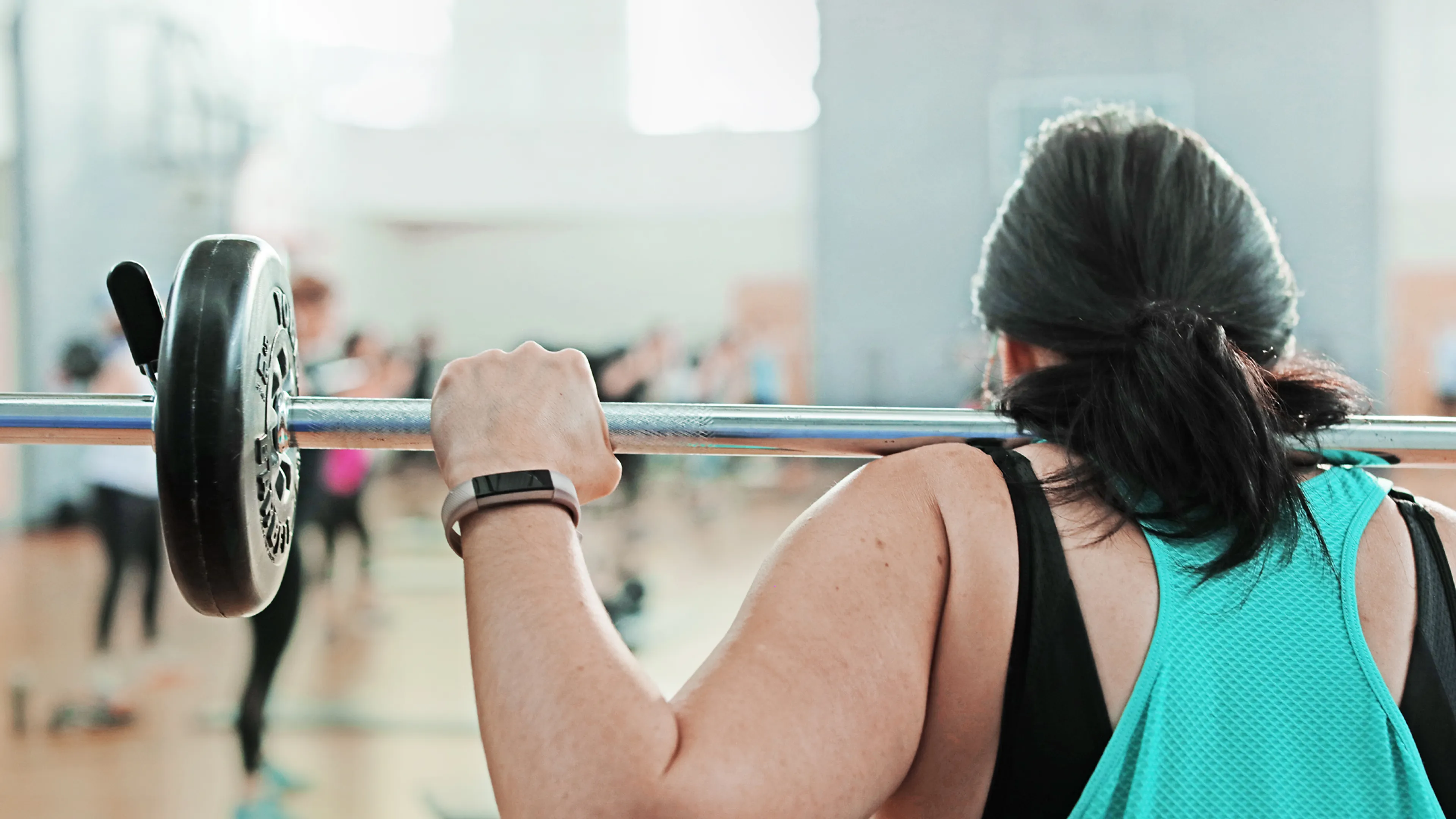 Back View of Woman Lifting Weights in a Class