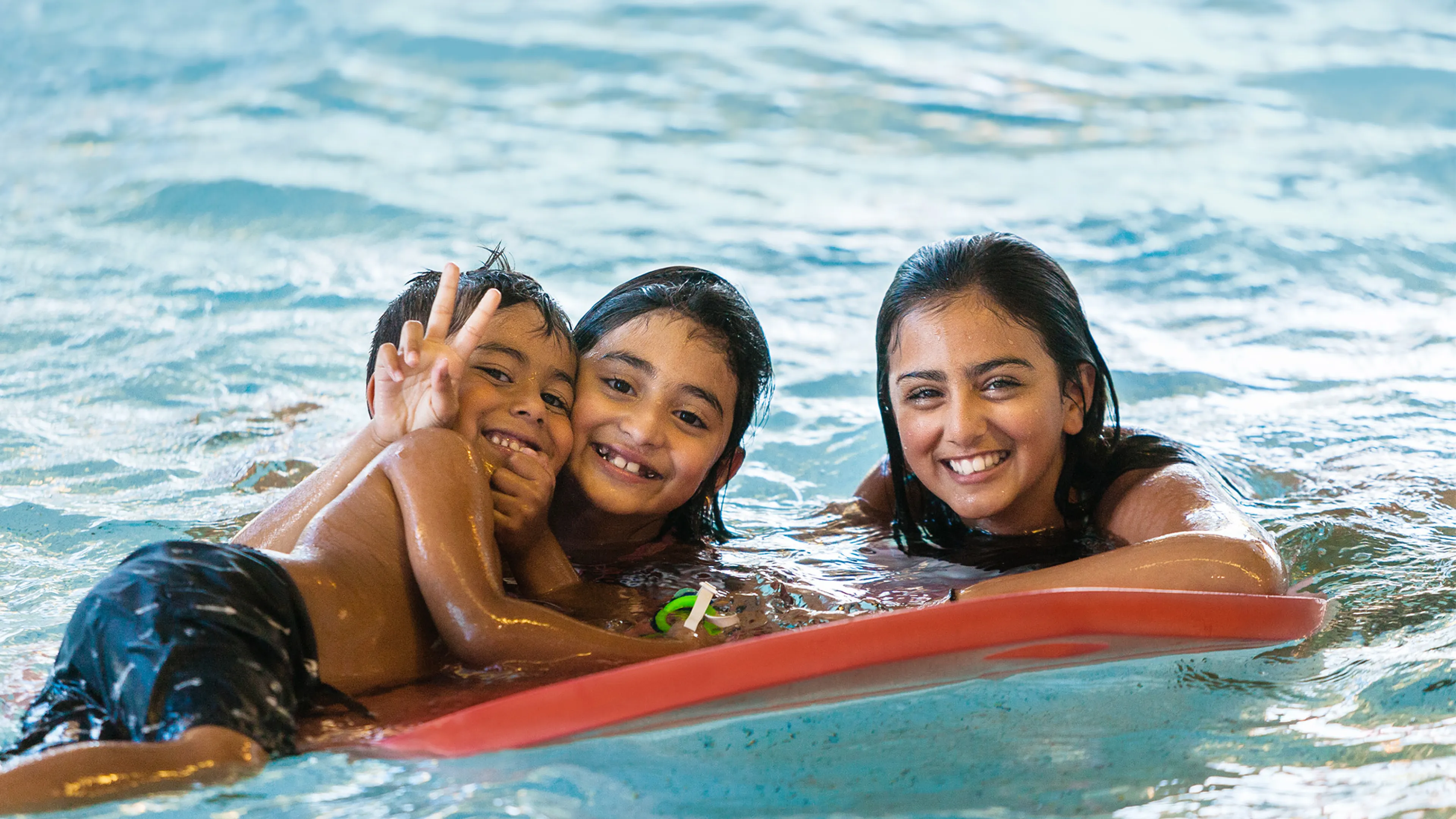 Three Kids Playing with a Flutter Board in the Pool