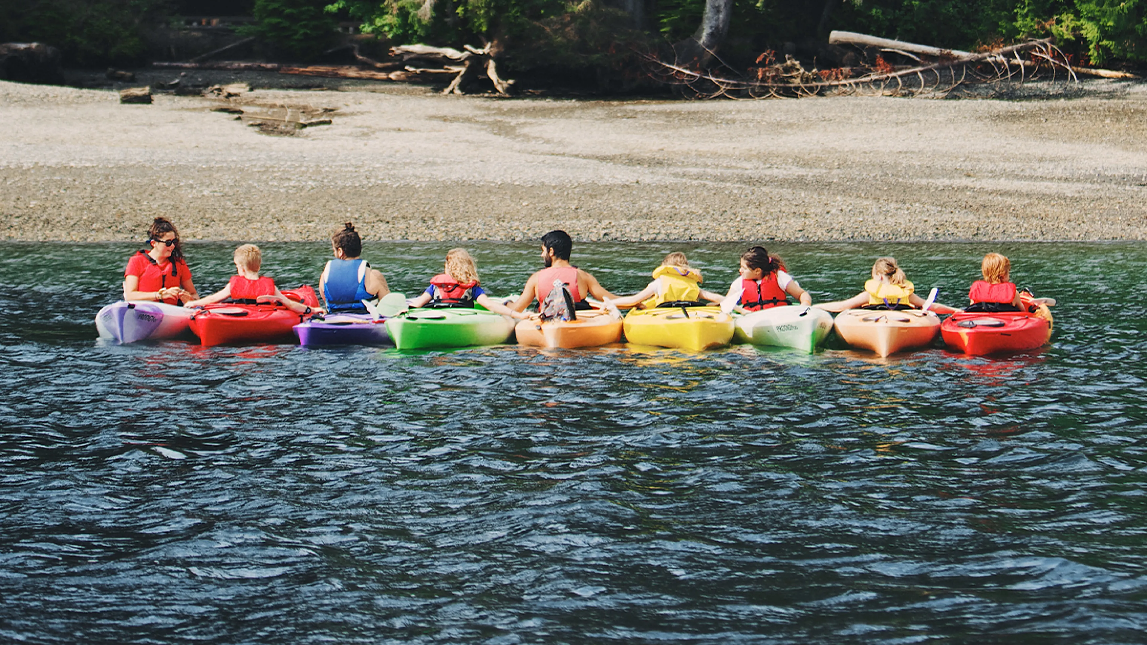 large group of people in a row of kayaks on the water