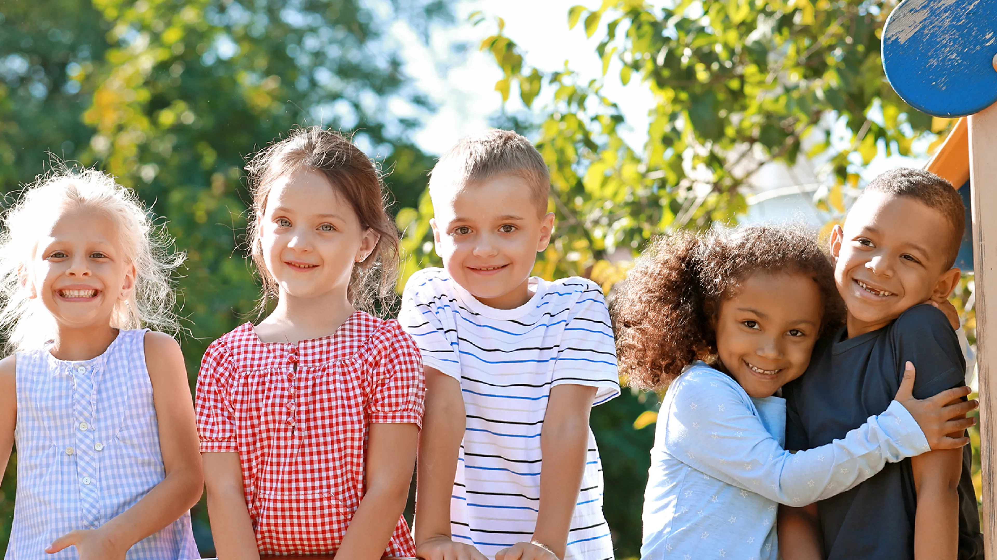 diverse group of children smiling while outside on sunny day