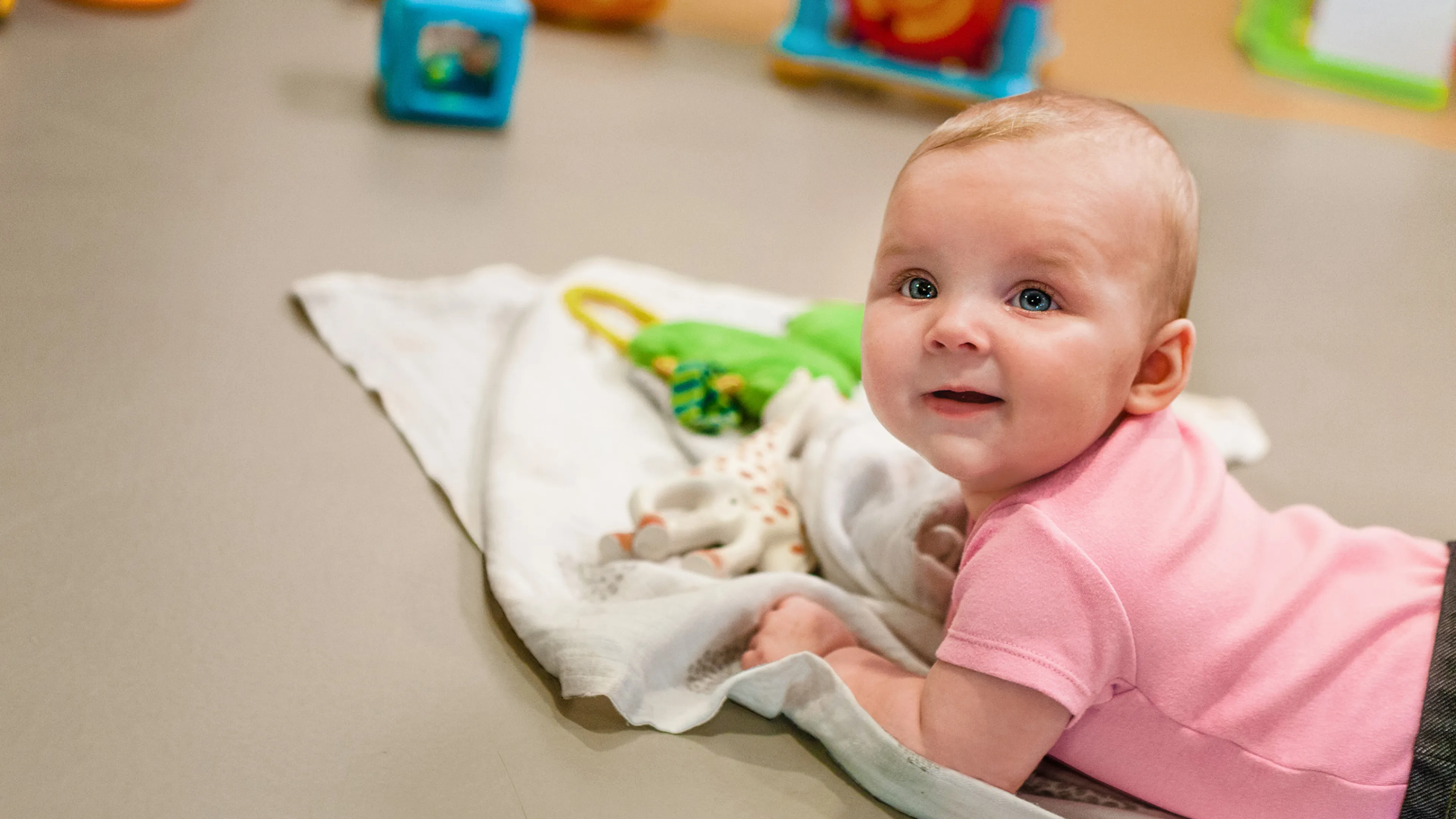 infant doing tummy-time on blanket with toys