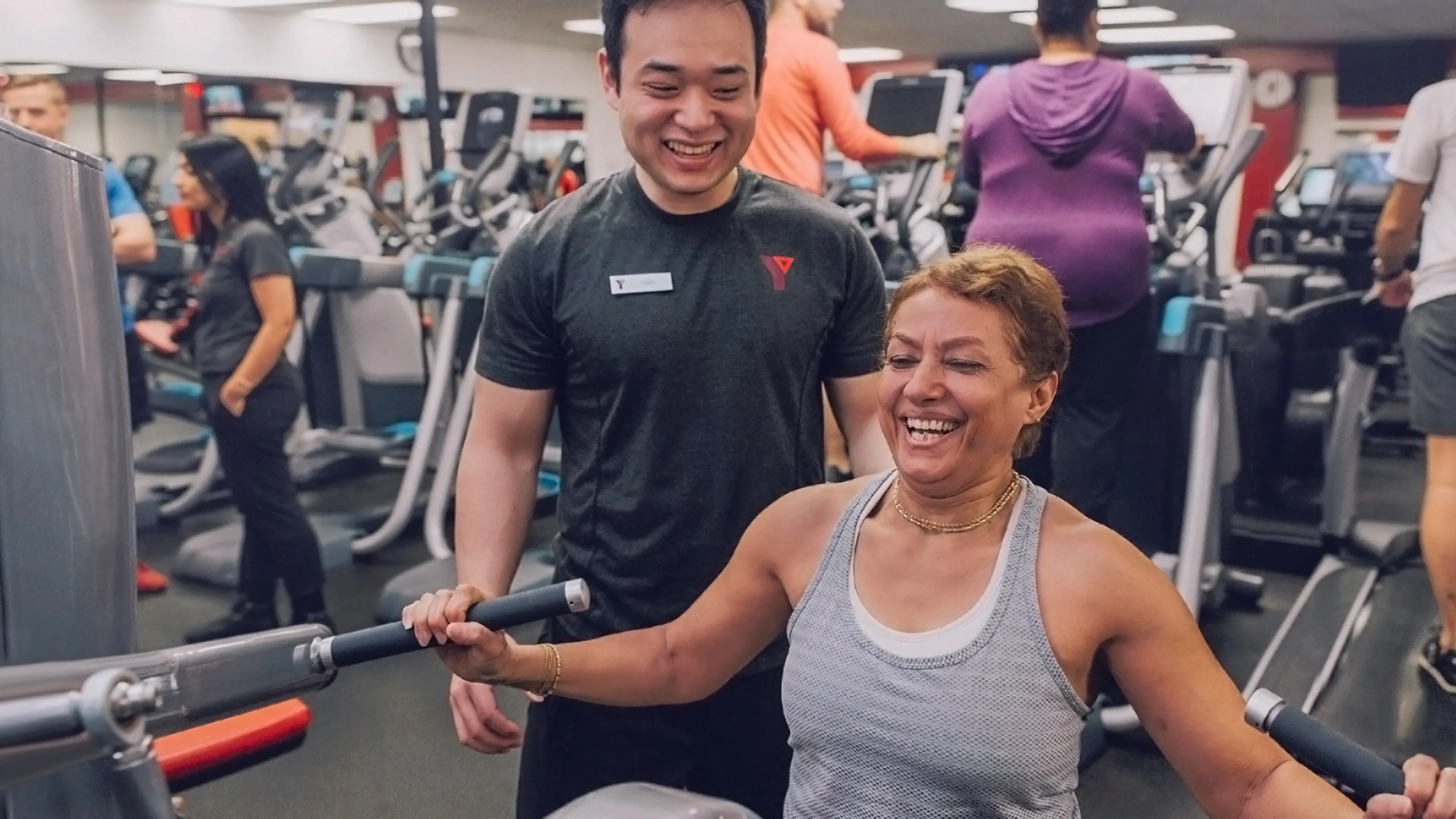 Fitness Staff With Woman Using Resistance Equipment