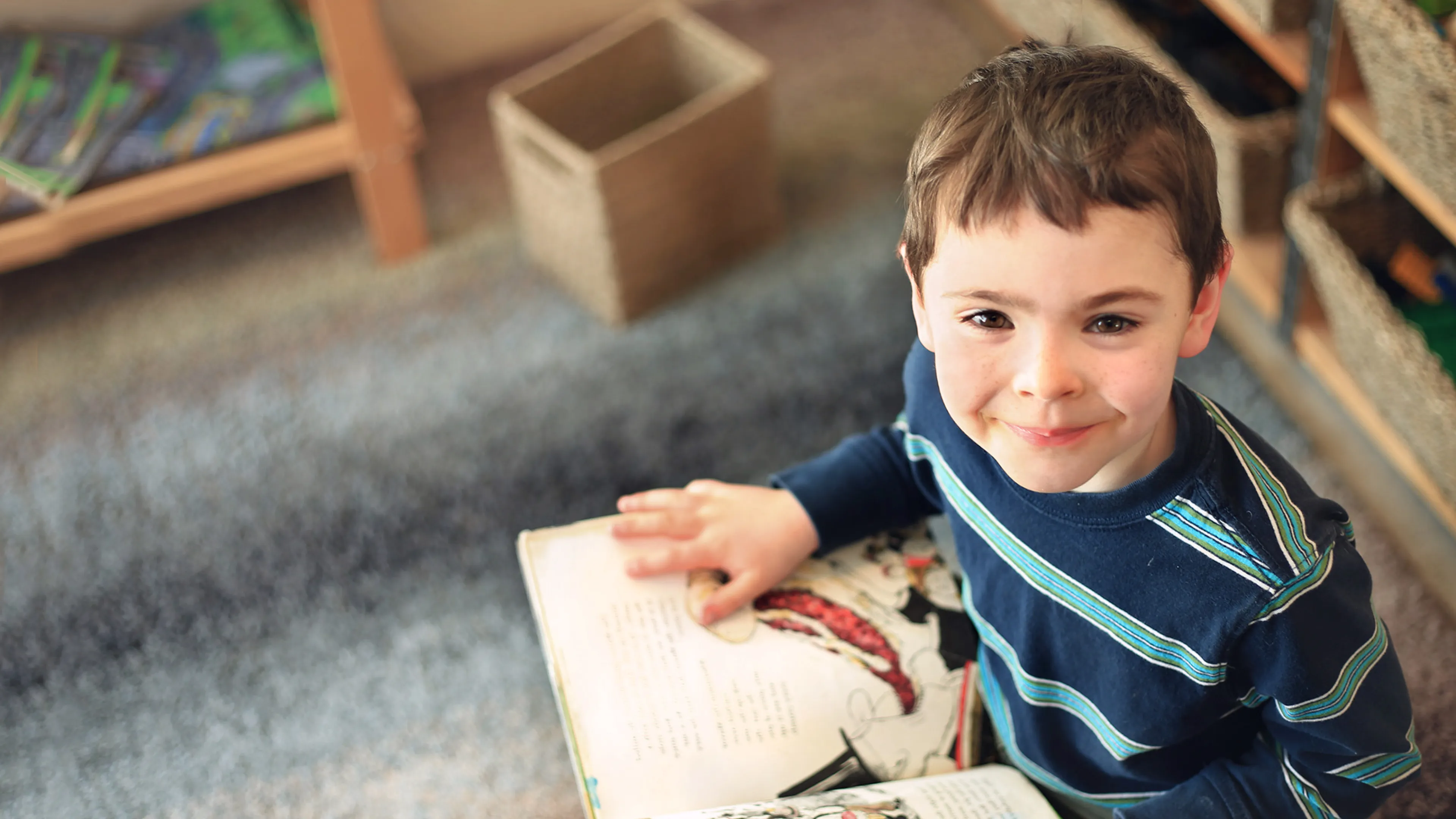 [Image] school aged boy sitting and reading a story