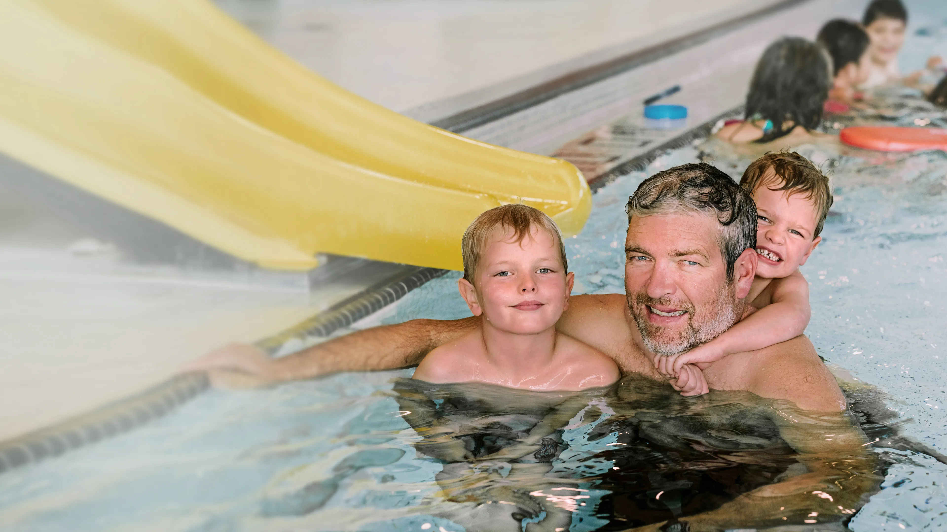 Father and two boys play in pool