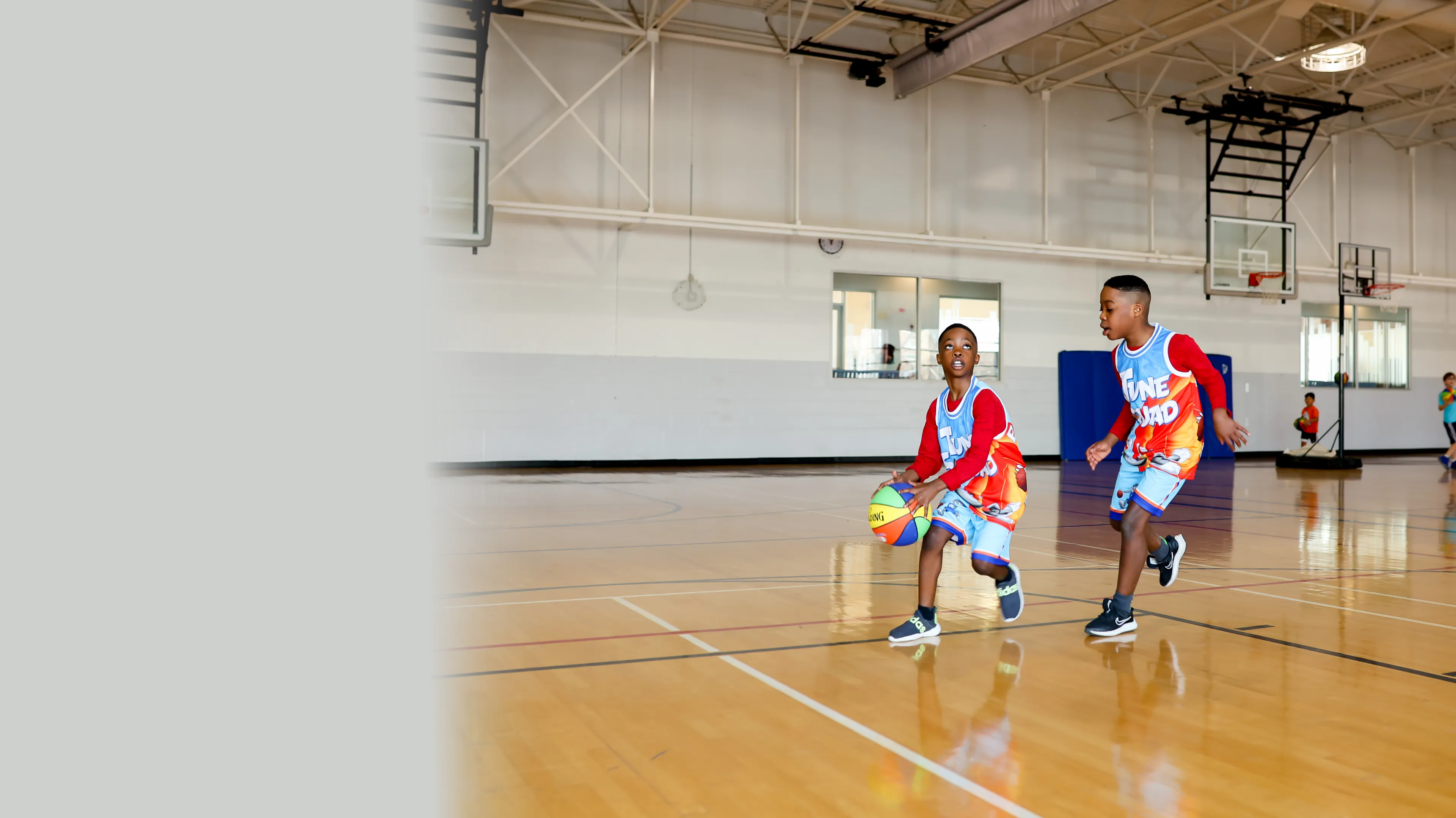 2 young boys playing basketball in the gymnasium