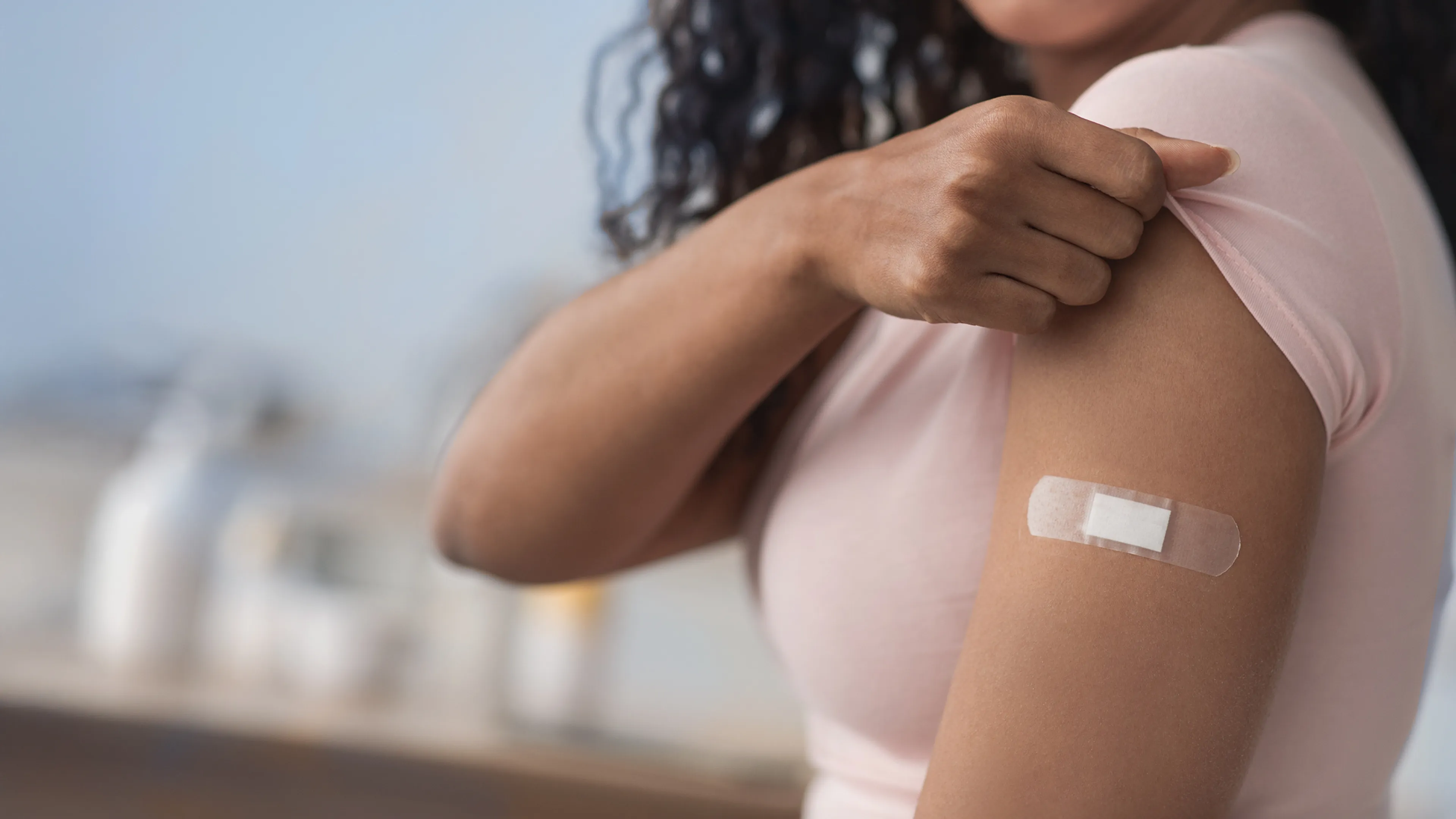 Image of a woman pulling up her sleeve to show bandage