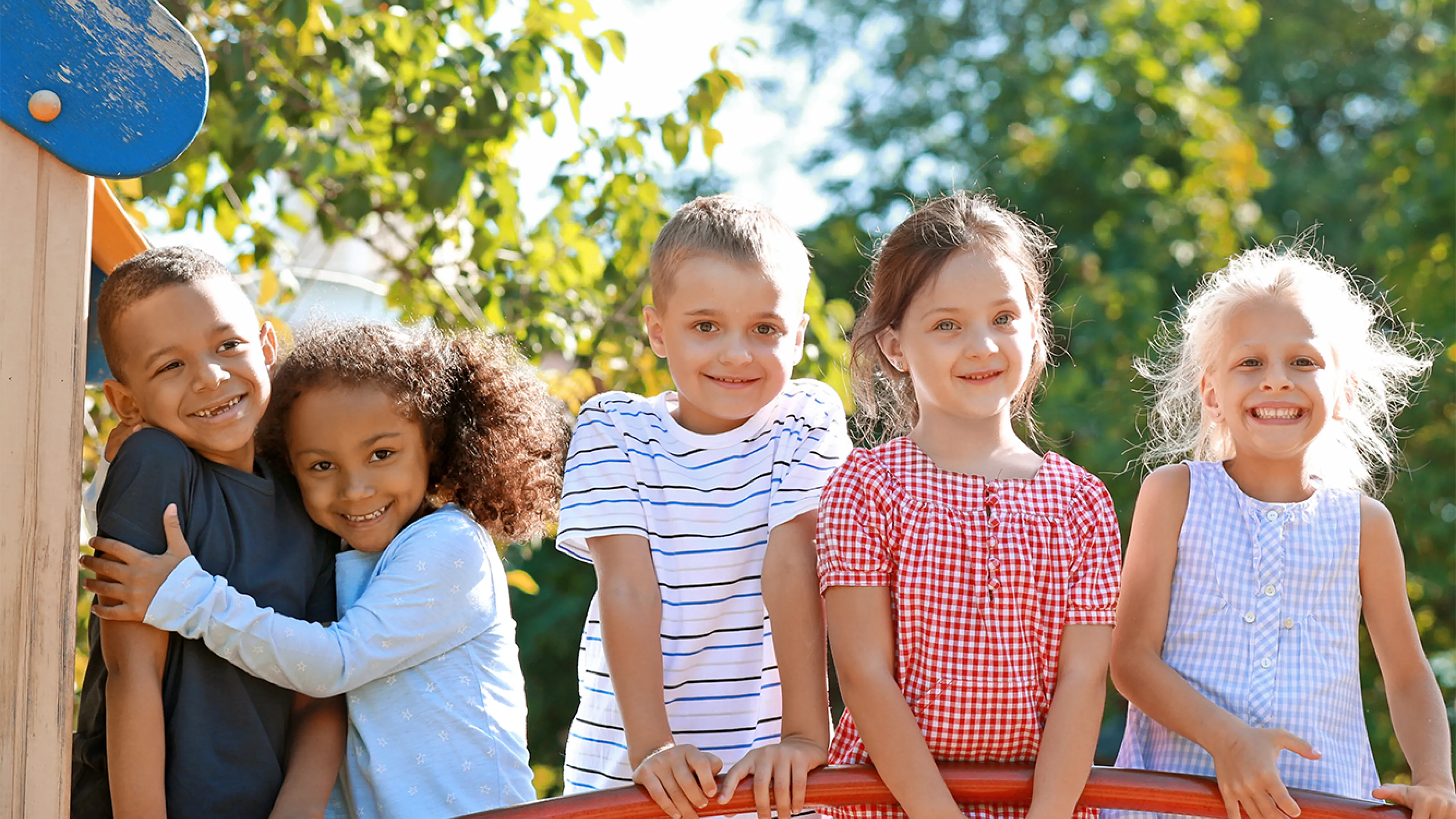 group of children smiling at camera playing in the sunshine