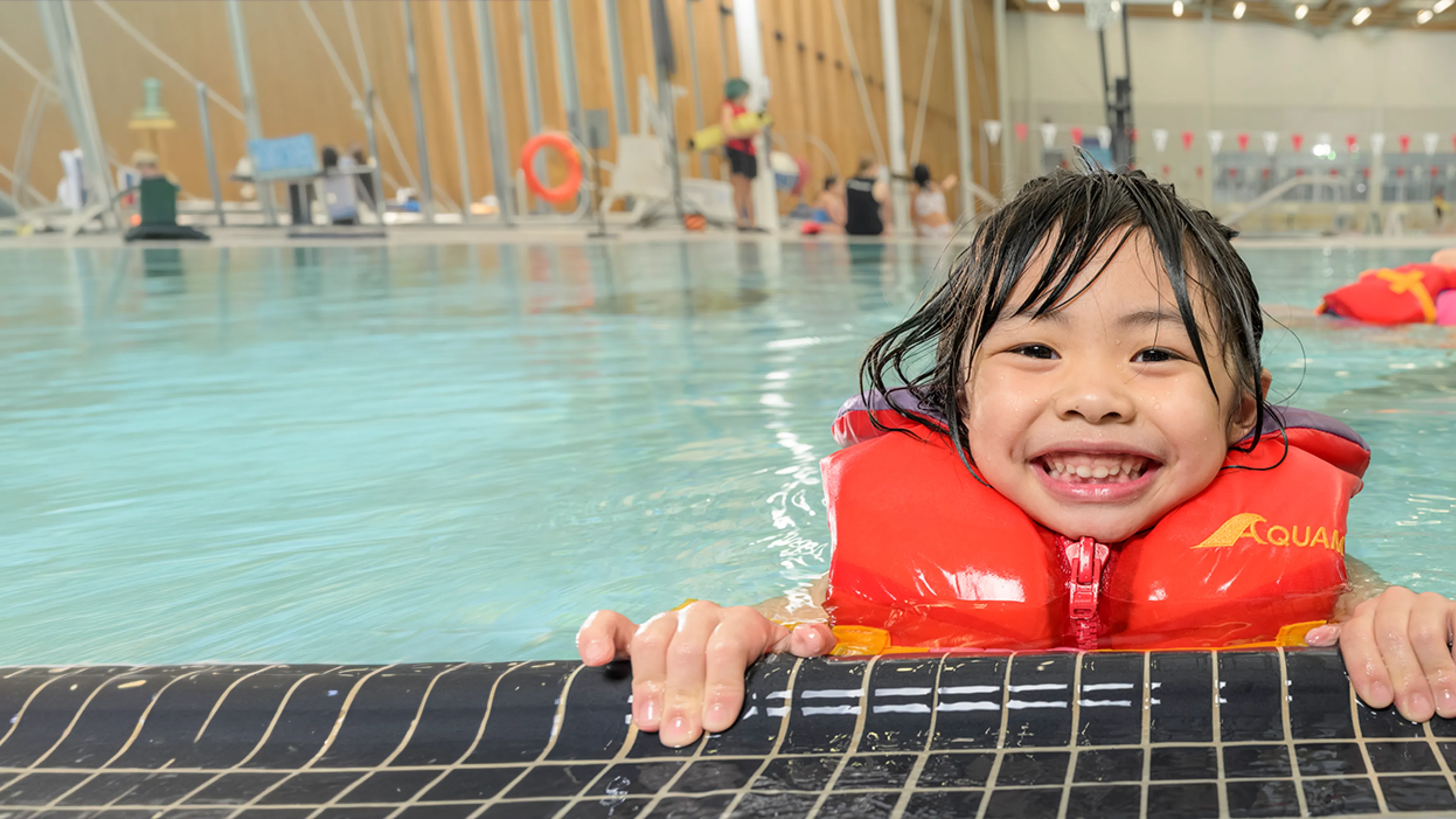 smiling child in pool at water's edge
