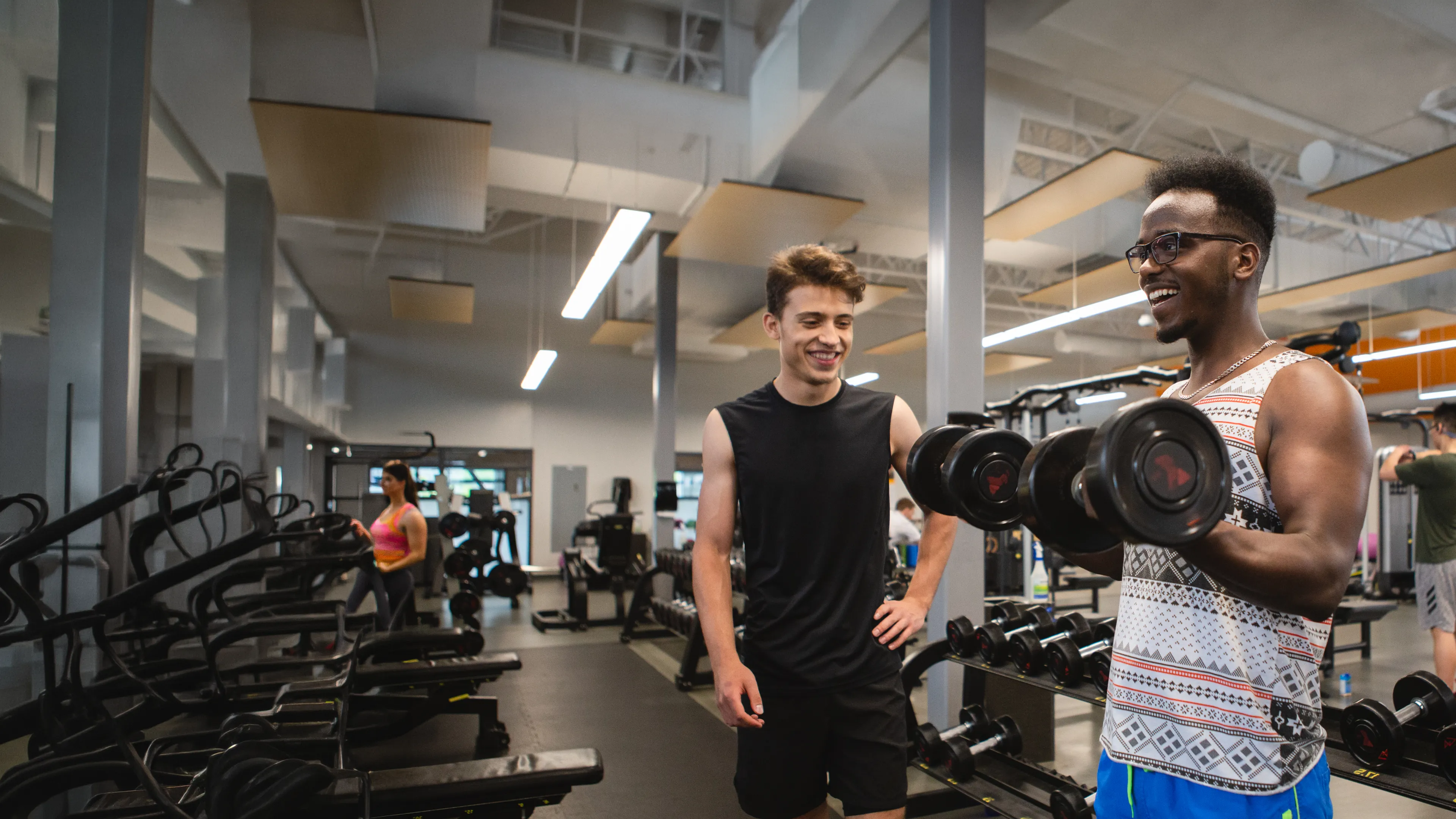 young male adults using dumbbells in a gym