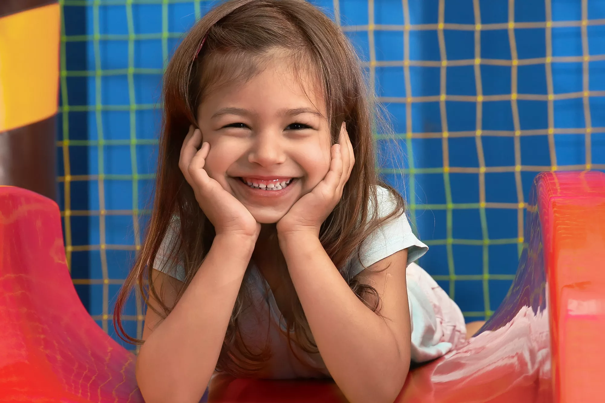 Child Smiling at the Top of a Red Slide