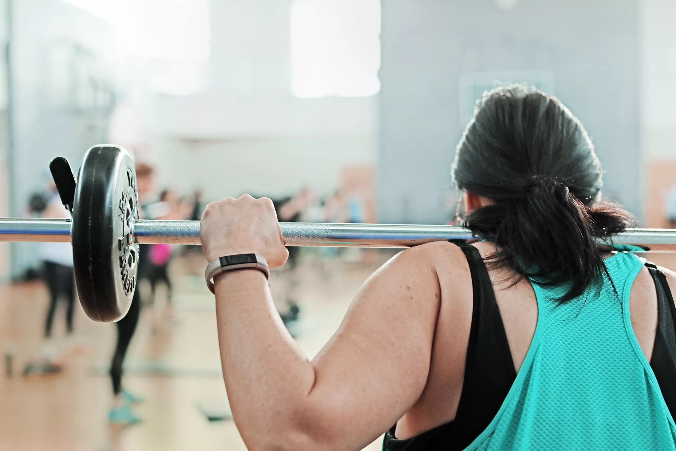 Back View of Woman Lifting Weights in a Class