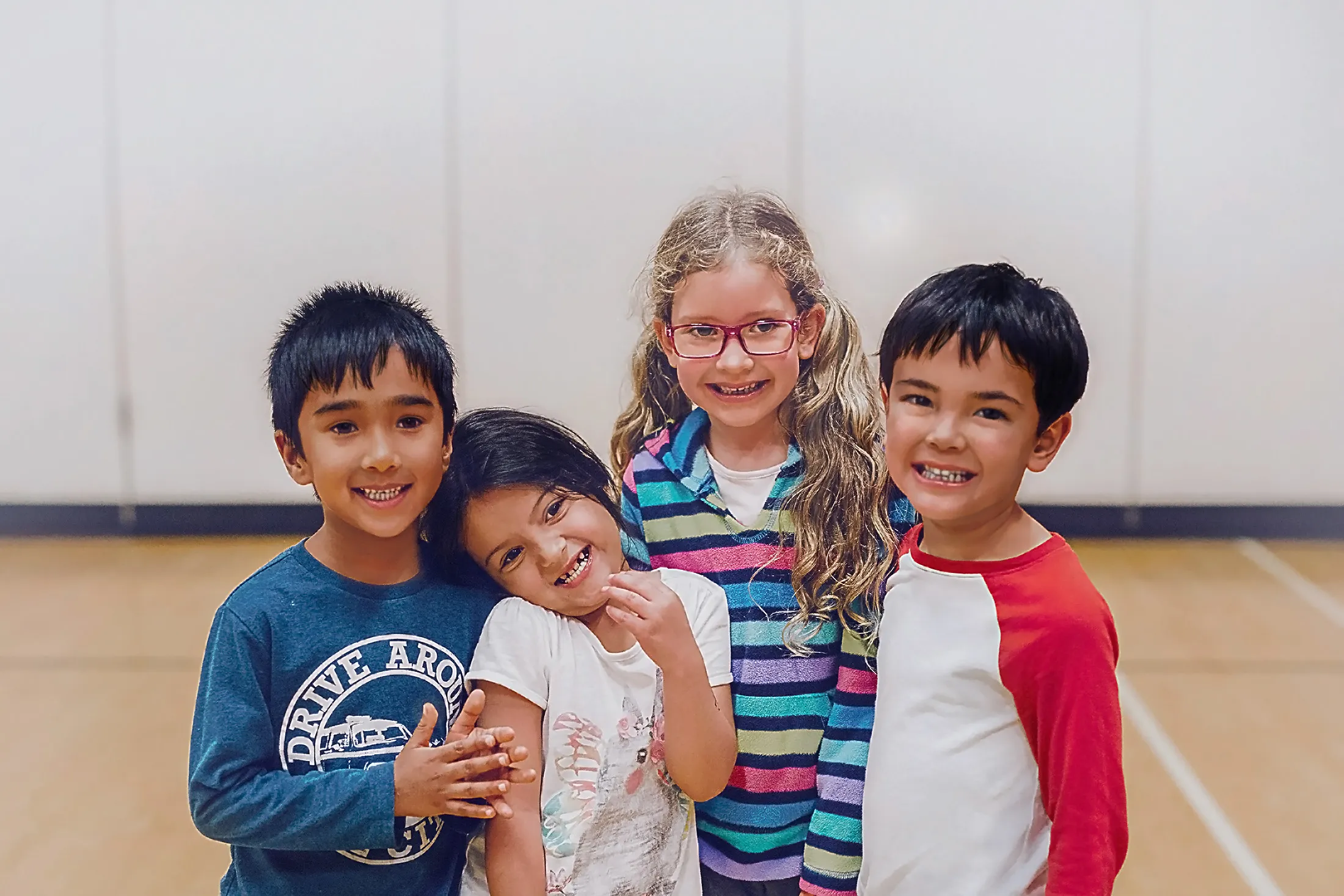 image of four kids smiling together in gymnasium