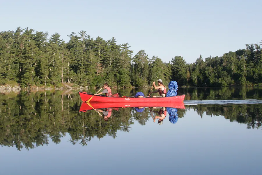two male campers on a canoe in calm water