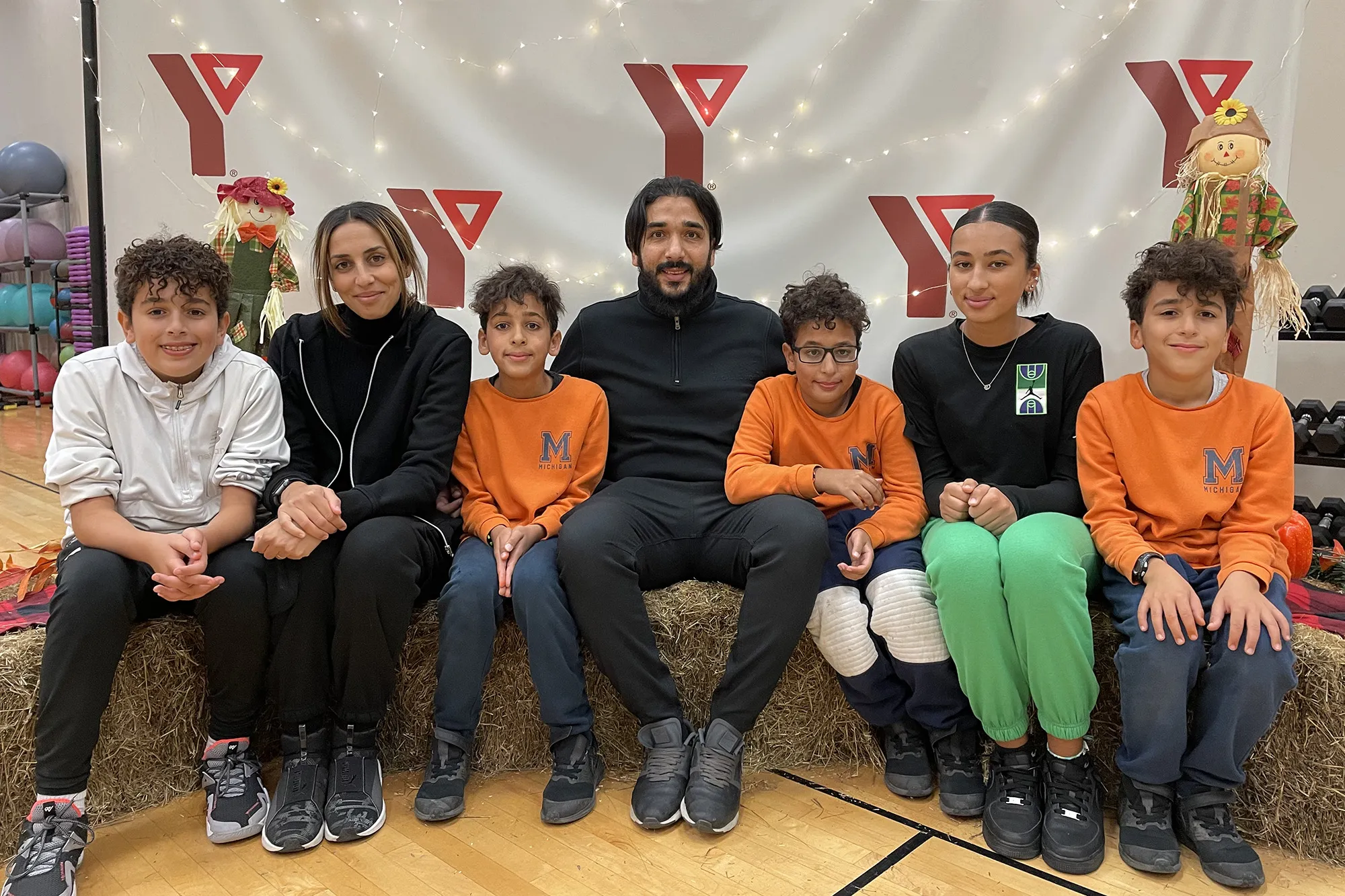 Fekiri family sits on hay bales art the Y Winnipeg Fall Community Celebration.