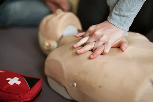 [Image] close-up of person performing chest compressions on CPR dummy