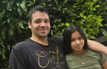 Robert and Sapphira pose in front of plant wall at the Downtown Y