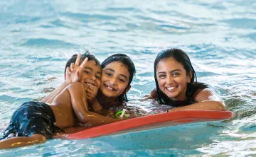 Three Kids Playing with a Flutter Board in the Pool