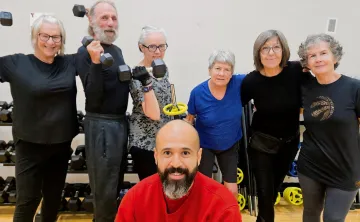 Y instructor, Javi, posing with Judy and class